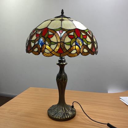 Tiffany amber Victorian floral scroll stained glass table lamp lit on bedside table